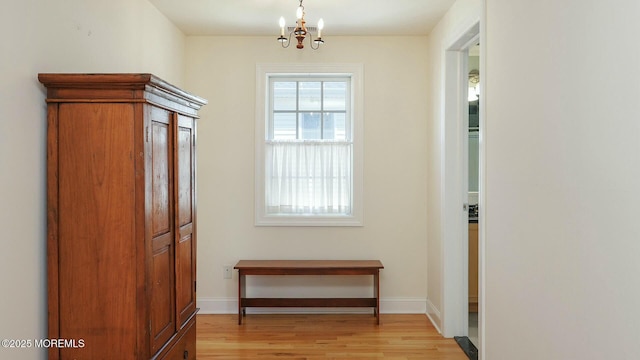 doorway with light wood-type flooring, baseboards, and a chandelier