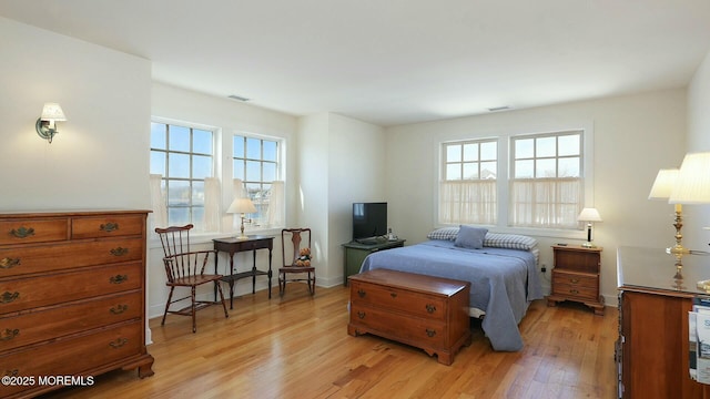 bedroom featuring light wood finished floors, visible vents, and baseboards