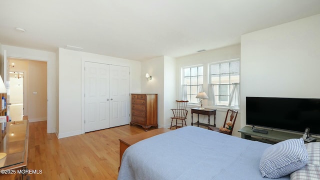 bedroom featuring light wood finished floors, baseboards, visible vents, and a closet