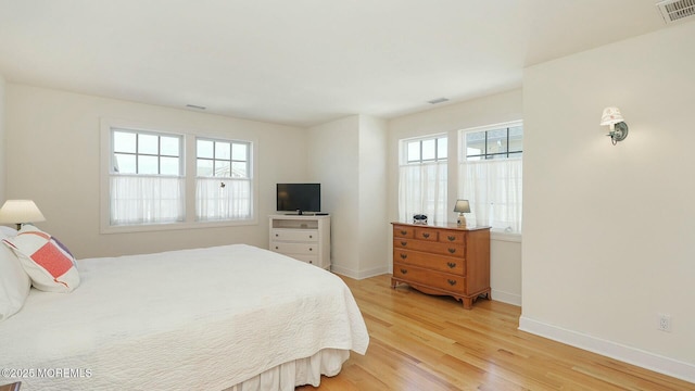 bedroom with light wood-style flooring, visible vents, and baseboards