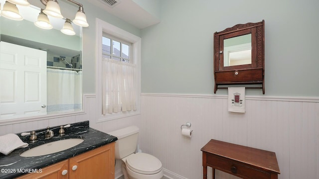 full bath with curtained shower, visible vents, toilet, wainscoting, and vanity