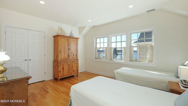 bedroom featuring light wood finished floors, visible vents, vaulted ceiling, a closet, and recessed lighting