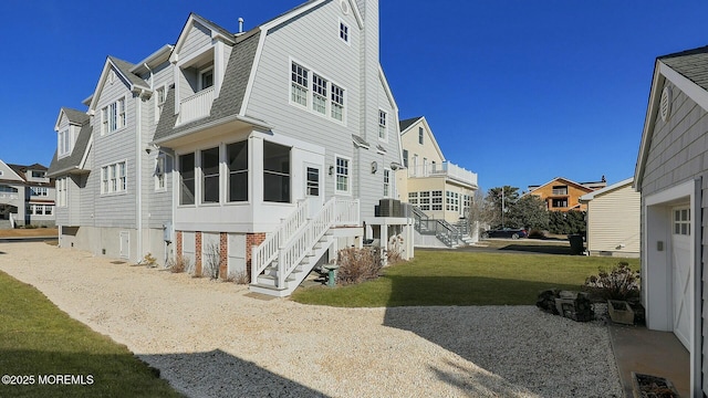 view of property exterior with a shingled roof, a lawn, a residential view, and a gambrel roof