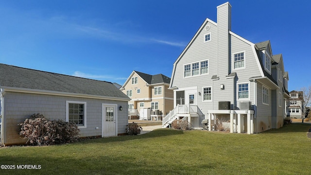 back of house with cooling unit, a lawn, a chimney, and a gambrel roof