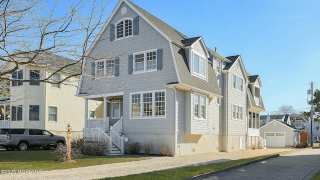 view of front facade featuring a garage, an outbuilding, roof with shingles, and a gambrel roof