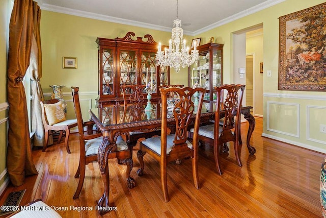 dining area featuring visible vents, crown molding, an inviting chandelier, and wood finished floors