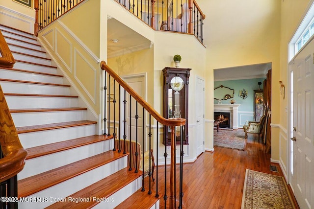 entryway with baseboards, hardwood / wood-style floors, stairs, a high ceiling, and a high end fireplace