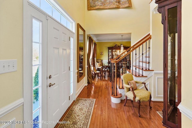 foyer entrance with stairs, a healthy amount of sunlight, wood finished floors, and crown molding