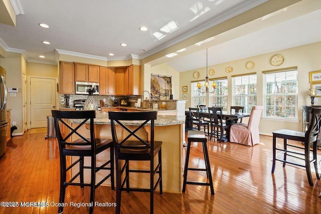 kitchen with stainless steel appliances, a breakfast bar area, backsplash, and crown molding