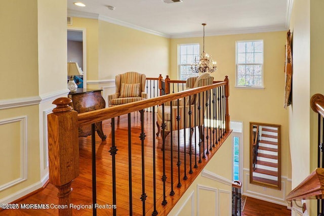 stairs with a notable chandelier, crown molding, and wood finished floors