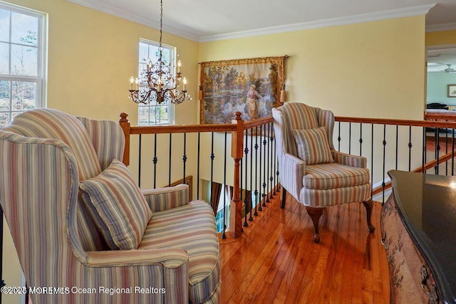 living area with a chandelier, wood finished floors, an upstairs landing, and crown molding