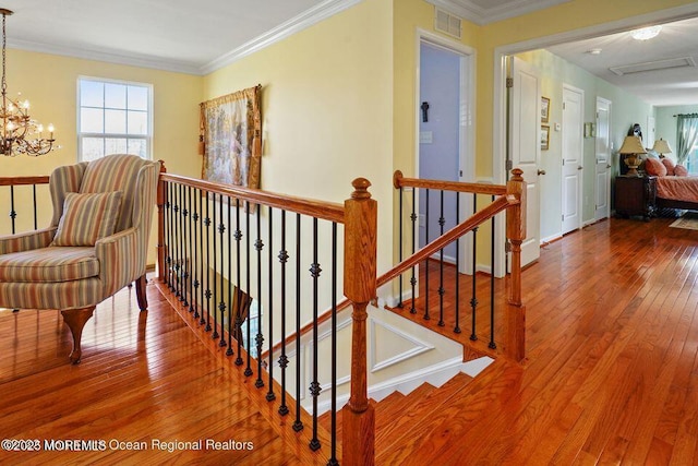 interior space with crown molding, visible vents, hardwood / wood-style floors, a chandelier, and baseboards