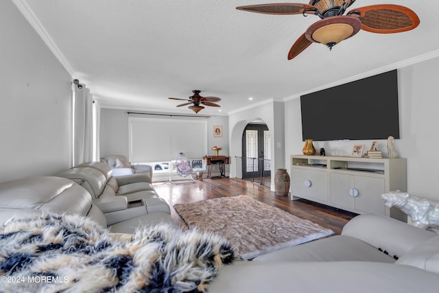 living room featuring arched walkways, ceiling fan, a textured ceiling, wood finished floors, and ornamental molding