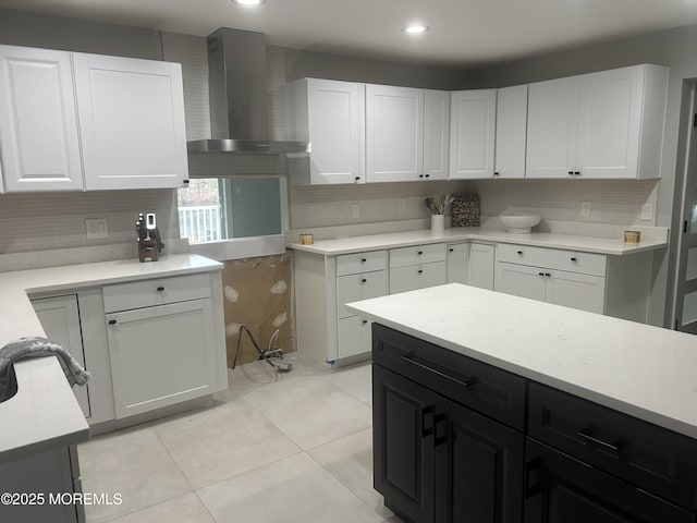 kitchen with light tile patterned floors, white cabinets, light countertops, backsplash, and wall chimney exhaust hood