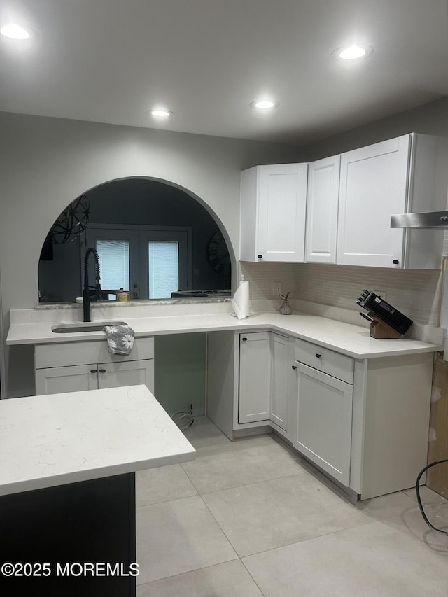 kitchen featuring light tile patterned floors, recessed lighting, a sink, white cabinets, and backsplash