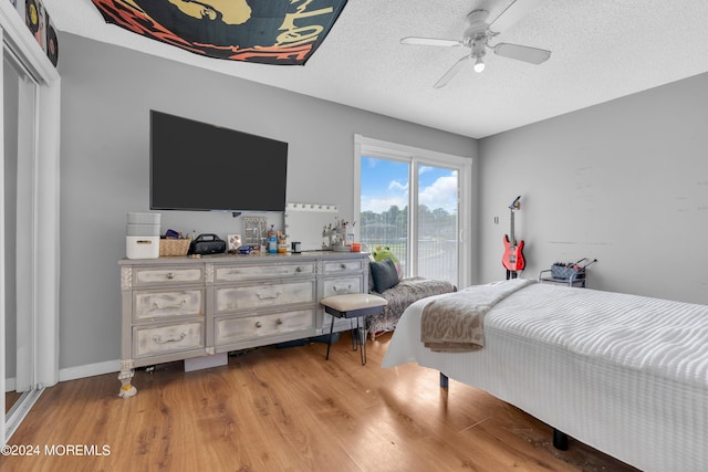 bedroom with light wood finished floors, a closet, a ceiling fan, a textured ceiling, and access to outside