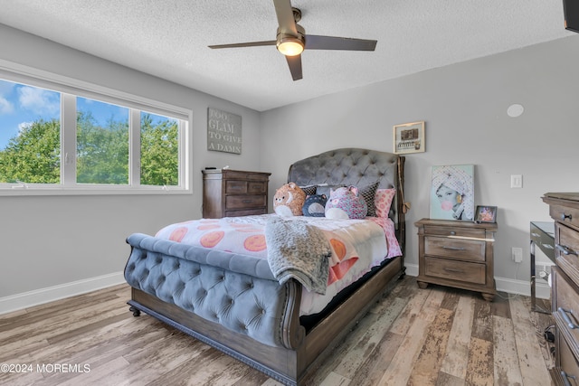 bedroom featuring ceiling fan, a textured ceiling, baseboards, and wood finished floors