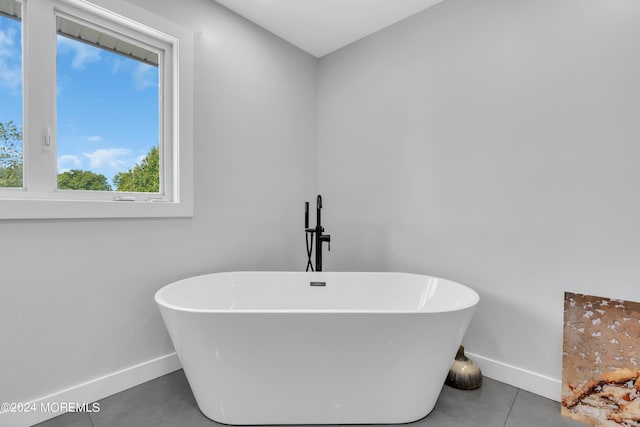 full bathroom with a soaking tub, tile patterned floors, and baseboards