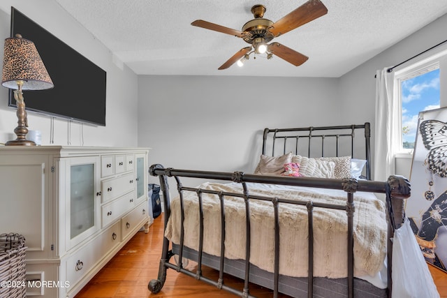 bedroom with a ceiling fan, a textured ceiling, and light wood finished floors