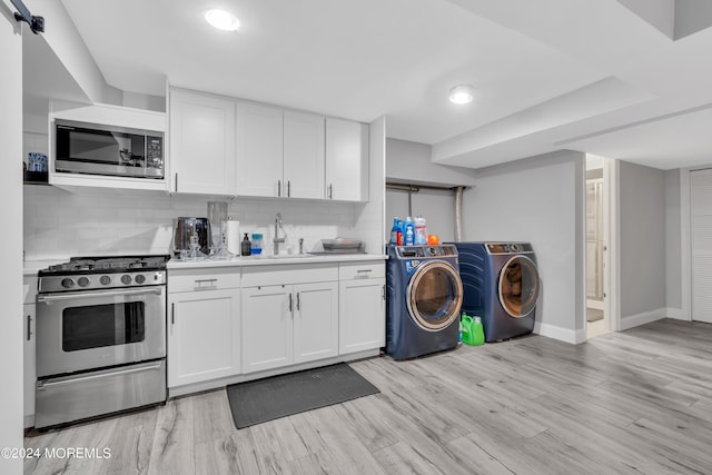 kitchen featuring washer and clothes dryer, a sink, stainless steel appliances, light countertops, and backsplash