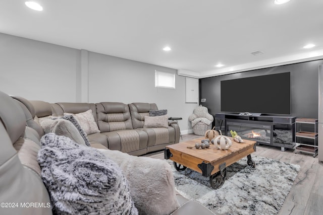 living room featuring recessed lighting, a glass covered fireplace, baseboards, and wood finished floors