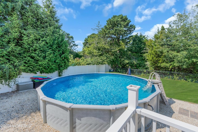 view of swimming pool featuring a fenced backyard, a lawn, and a fenced in pool