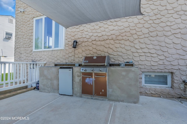 view of patio with an outdoor kitchen, fence, and a grill