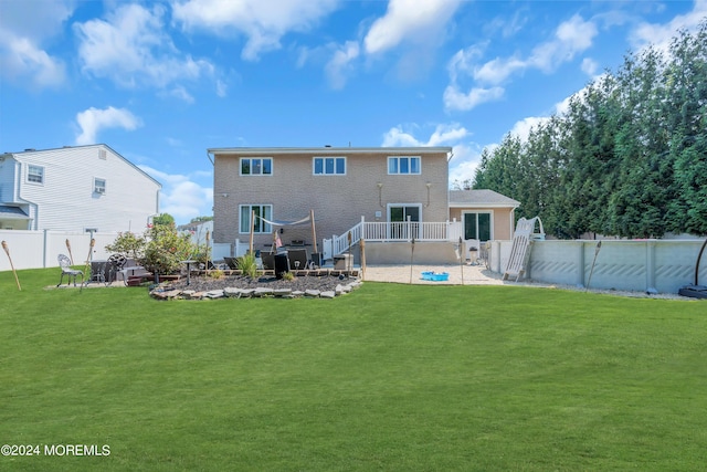 back of house featuring a patio area, a fenced backyard, a fenced in pool, and a yard