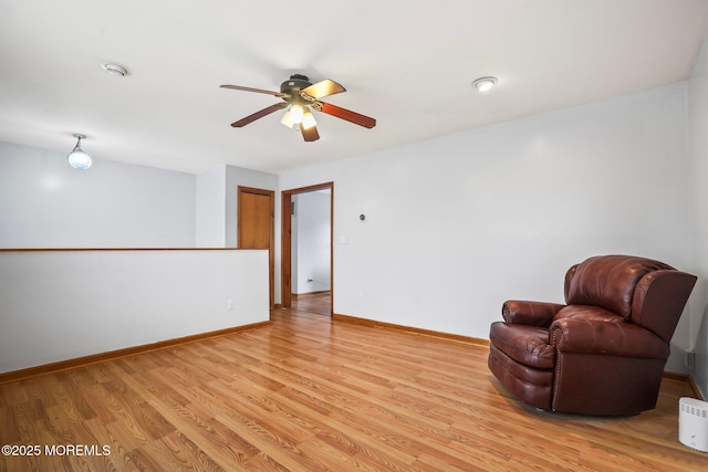 living area featuring ceiling fan, light wood-style flooring, and baseboards