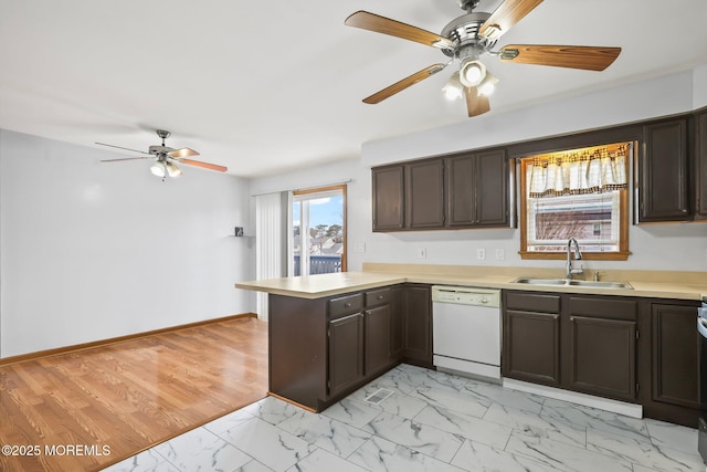 kitchen with marble finish floor, light countertops, a sink, dishwasher, and a peninsula