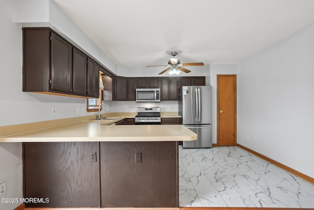 kitchen with appliances with stainless steel finishes, marble finish floor, light countertops, dark brown cabinets, and a sink