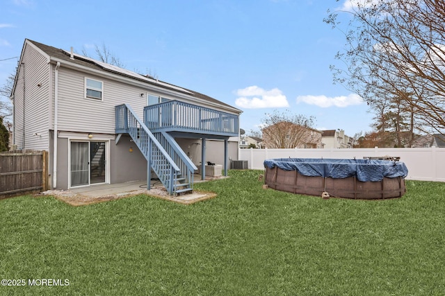 back of property with stairs, a deck, a lawn, and a fenced backyard