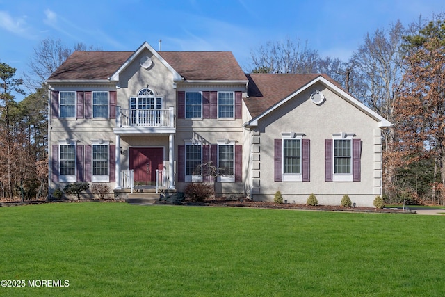 view of front of house with roof with shingles, a balcony, a front lawn, and stucco siding