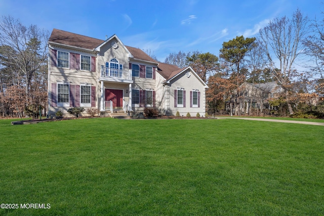 colonial house with a balcony and a front lawn