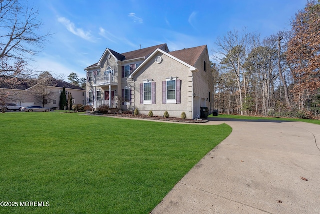 view of front of house featuring a garage, driveway, a front yard, and a balcony