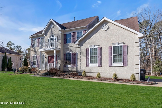 view of front of house with a balcony, a front lawn, and stucco siding