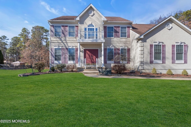 view of front of home featuring a front lawn, a balcony, and stucco siding