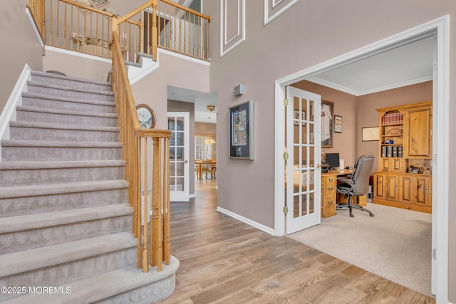 stairway featuring baseboards, french doors, wood finished floors, and crown molding