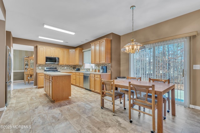 kitchen featuring tasteful backsplash, appliances with stainless steel finishes, a center island, light countertops, and pendant lighting