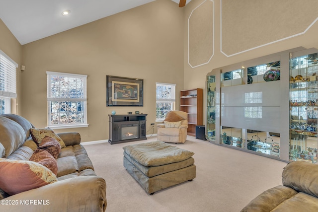 carpeted living area featuring high vaulted ceiling, recessed lighting, a glass covered fireplace, and baseboards