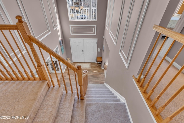 staircase featuring a chandelier, a towering ceiling, and baseboards