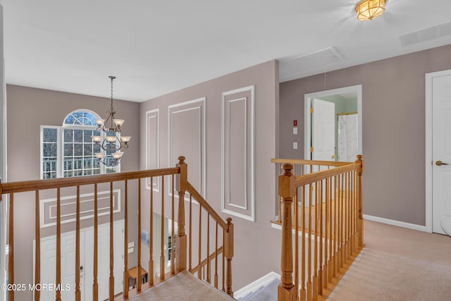 corridor with carpet floors, attic access, visible vents, and an upstairs landing