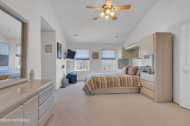 bedroom featuring light carpet, visible vents, vaulted ceiling, and a ceiling fan