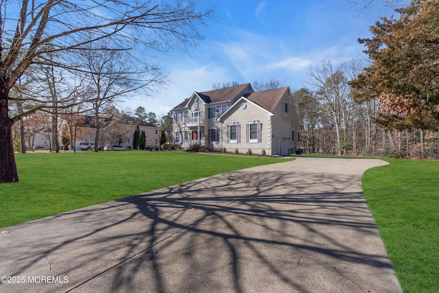 view of front facade with concrete driveway and a front lawn