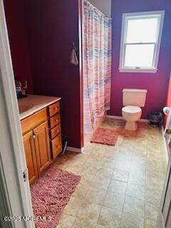 bathroom with curtained shower, toilet, and baseboards