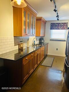 kitchen with decorative backsplash, glass insert cabinets, brown cabinets, and a sink