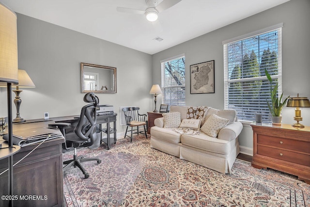 office space featuring baseboards, visible vents, a ceiling fan, and wood finished floors