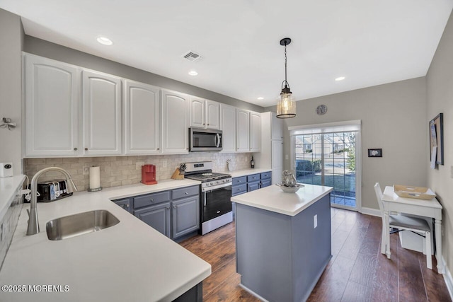 kitchen with visible vents, a kitchen island, appliances with stainless steel finishes, dark wood-type flooring, and backsplash