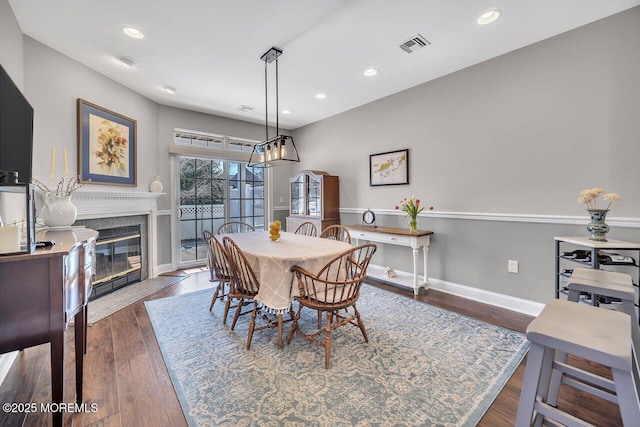 dining area featuring baseboards, visible vents, a fireplace with flush hearth, wood finished floors, and recessed lighting