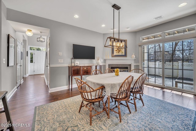 dining area featuring baseboards, visible vents, dark wood-type flooring, and a glass covered fireplace